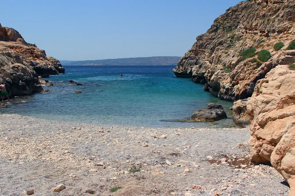 Koutalas beach shows a long sandy expanse backed by coastal cliffs overlooking the Aegean Sea in Crete.